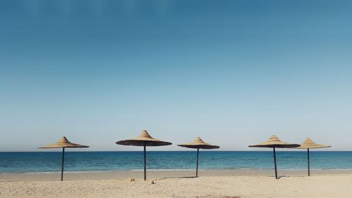 Sunshades at beach against clear sky