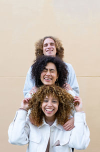 Diverse man and women standing behind each other showing heads with curly hair and laughing