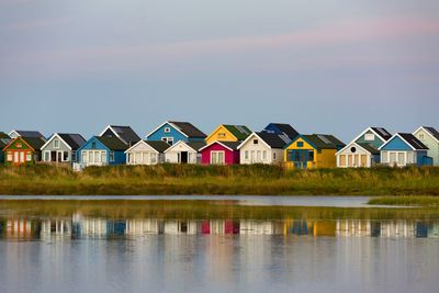 Buildings by lake against sky