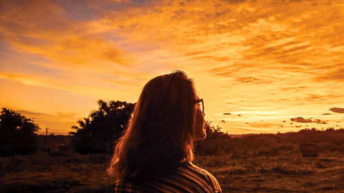Rear view of woman standing against orange sky