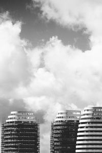 Low angle view of skyscrapers against cloudy sky