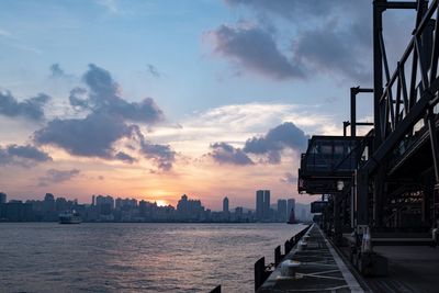 Buildings by sea against sky during sunset