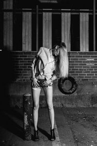 Young woman standing on footpath at night