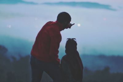 Side view of father with daughter against sky