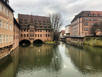 Bridge over canal amidst buildings against sky