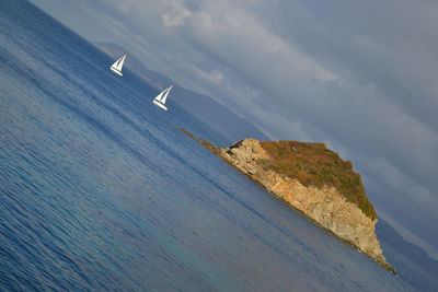 Rock formation on sea against cloudy sky