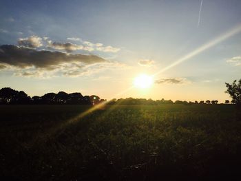 Scenic view of grassy field against sky at sunset