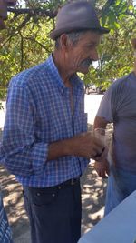 Midsection of man holding hands while standing against trees