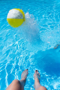 Low section of woman with ball in swimming pool