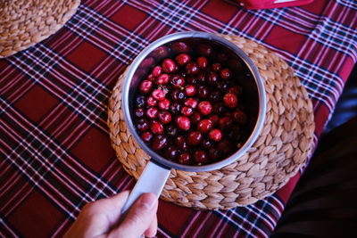 High angle view of hand holding strawberries in basket