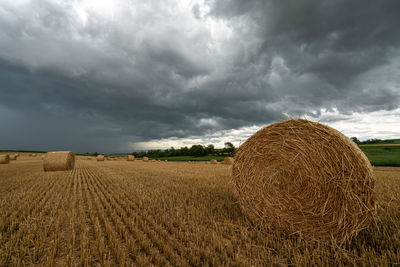 Hay bales on field against sky