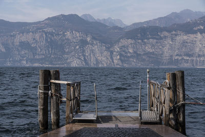 Wooden posts in sea against mountains