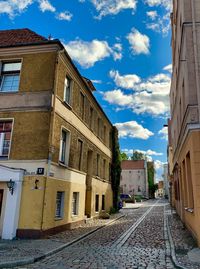 Empty road amidst buildings in city against sky