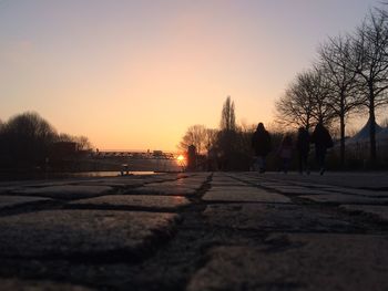 Road by silhouette trees against clear sky during sunset