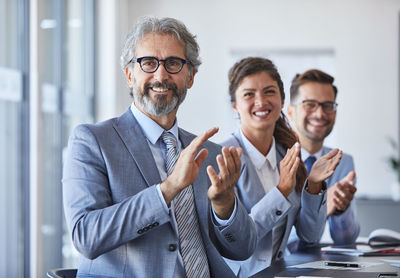 Portrait of smiling business colleagues applauding at office