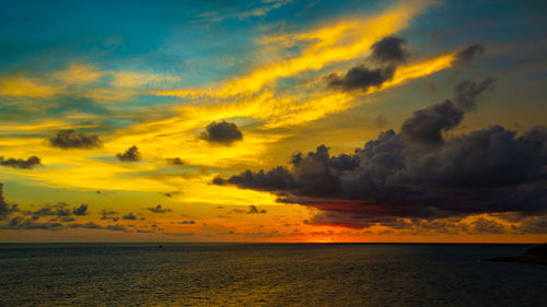 Scenic view of sea against dramatic sky during sunset