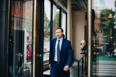 Mature businessman looking away while walking through doorway