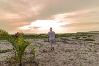 Man standing on land against sky during sunset