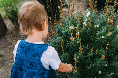 Little girl walks in the garden among beautiful evergreen southern plants