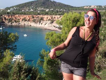 Portrait of smiling young woman in sunglasses against mountains