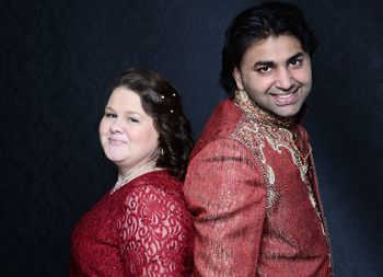 Portrait of smiling couple in traditional clothing standing on black background