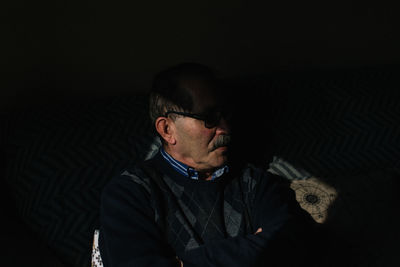 Thoughtful man sitting in darkroom