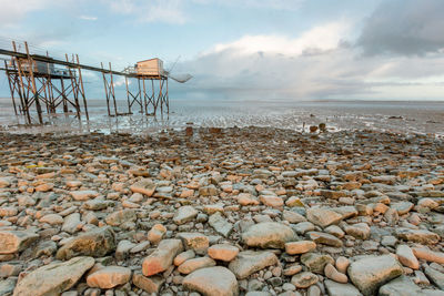 Scenic view of sea and fishing hut against sky