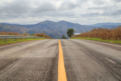 Empty road by mountains against sky