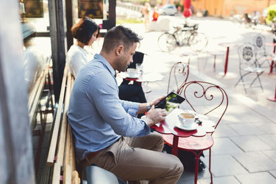 Businessman using digital tablet at sidewalk cafe