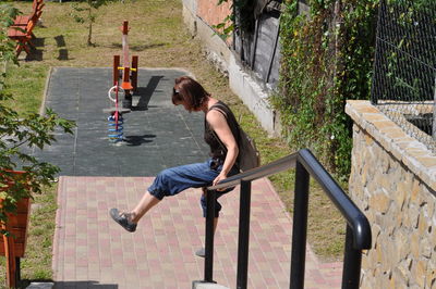Woman sliding on railing by playground
