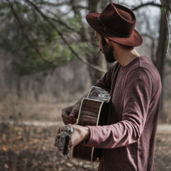 Midsection of man with umbrella in forest