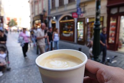 Close-up of coffee cup on street in city