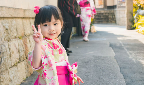 Portrait of cute girl gesturing while standing on road