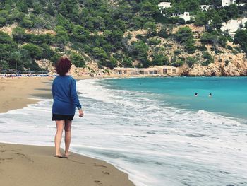 Rear view of woman walking on windy beach