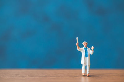 Full length of man standing against blue wall