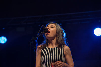 Beautiful young woman with arms outstretched at night