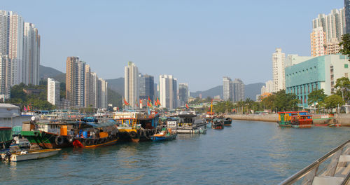 Boats in city by buildings against clear sky