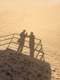 Shadow of people on sand at beach