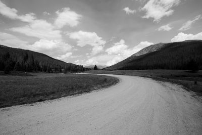 Road amidst field against sky