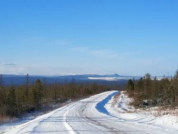 Road leading towards snowcapped mountain against sky