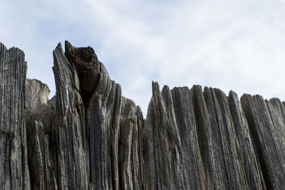 Low angle view of wood against cloudy sky