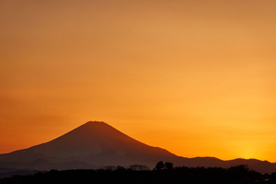 Scenic view of silhouette mountains against orange sky