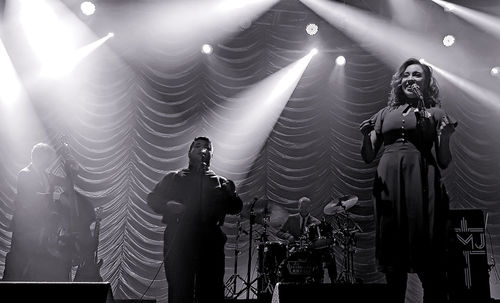 Low angle view of woman standing by illuminated lighting equipment at night