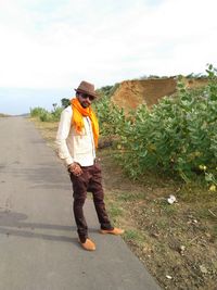 Full length of young man standing on road against sky