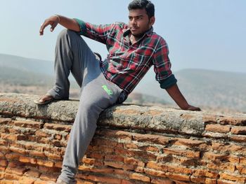 Full length of young man against wall against clear sky