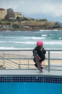 Man in swimming pool by sea against sky