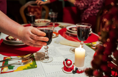 Midsection of man holding wine glass on table