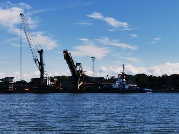 Cranes at commercial dock against sky