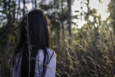 Rear view of woman with long brown hair against trees