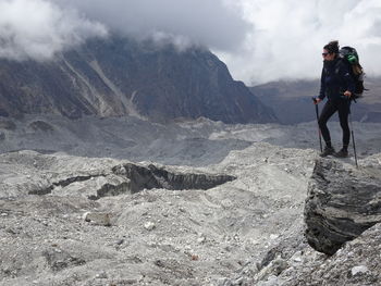 Rear view of man standing on mountain against sky